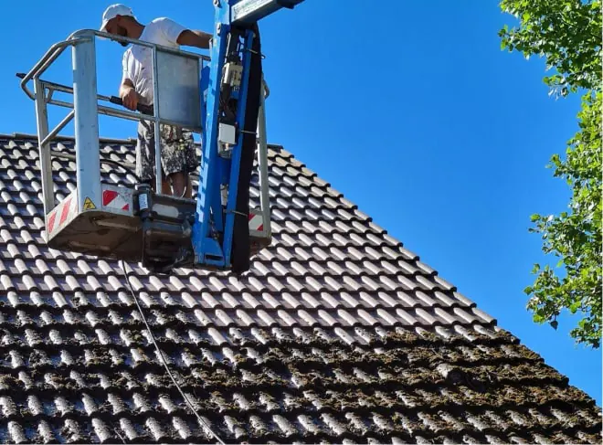 Démoussage d'une toiture en tuiles depuis une nacelle élévatrice