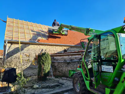 Chantier de couverture avec engin de levage sur une maison en pierre
